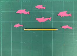 Sobre fondo verde, hay 6 recortes con forma de delfin de color rosa, pieza de Evripides & His Trajedis